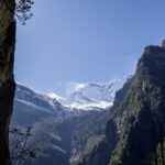 Snow-capped mountains surrounded by rocky cliffs and greenery