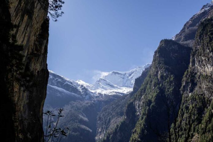 Snow-capped mountains surrounded by rocky cliffs and greenery