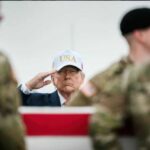 A man in a USA hat saluting during a military ceremony