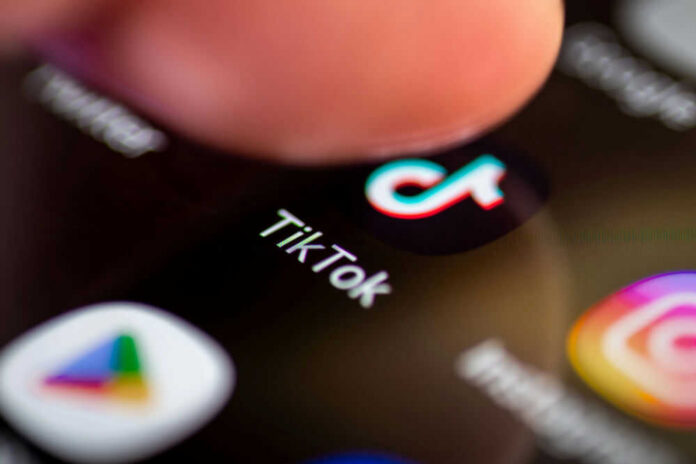 Finger tapping TikTok app on a smartphone screen