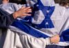 Netanyahu Threatens NYT in Scandalous Defamation Row People holding an Israeli flag together, showcasing unity and cultural pride