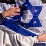 Netanyahu Threatens NYT in Scandalous Defamation Row People holding an Israeli flag together, showcasing unity and cultural pride