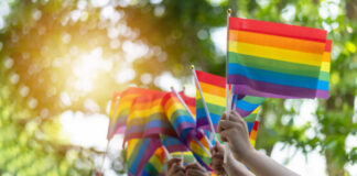 Hands waving rainbow pride flags outdoors