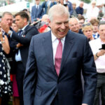 smiling man in a suit walking through a crowd