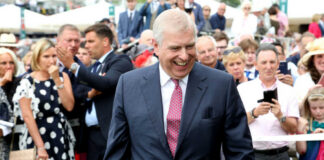 smiling man in a suit walking through a crowd