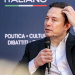 Man in suit holding microphone at event indoors