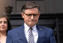 A man in suit and tie, looking serious.