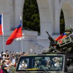 Soldiers in military vehicle during a parade with Taiwanese flags in the background