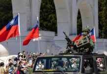Soldiers in military vehicle during a parade with Taiwanese flags in the background
