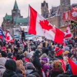 Crowd of people waving Canadian flags during an outdoor event