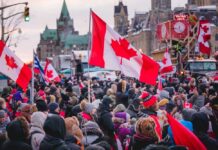 Crowd of people waving Canadian flags during an outdoor event