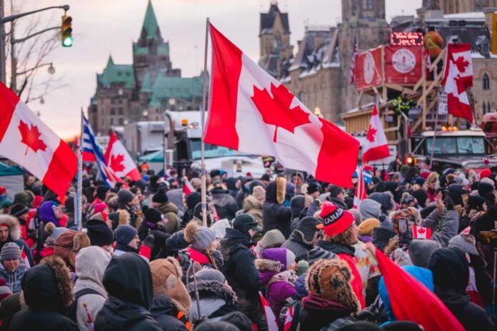 Crowd of people waving Canadian flags during an outdoor event