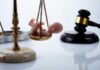 Scales of justice with a small baby figurine on one side and a gavel in the background