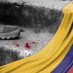 A military boot on concrete steps with blood stains and a Colombian flag draped nearby