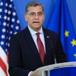 Becerra’s Campaign Cash Mystery Deepens Government official speaking at a podium with flags in the background