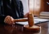 Intense Media Circus Masks Key Legal Fight A judge's hand holding a gavel in a courtroom setting