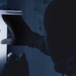 Tech-Savvy Burglars Exploit Social Media Clues A gloved hand attempting to unlock a door in low light