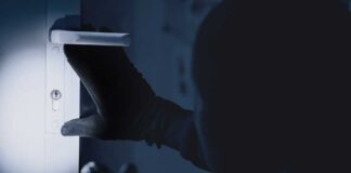 A gloved hand attempting to unlock a door in low light