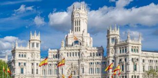 A grand historic building with flags in front and a fountain