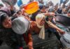 Drone Assault Turns Soup Kitchen Into Bloodbath women and children reach with pots at a crowded aid distribution