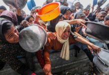 Drone Assault Turns Soup Kitchen Into Bloodbath women and children reach with pots at a crowded aid distribution