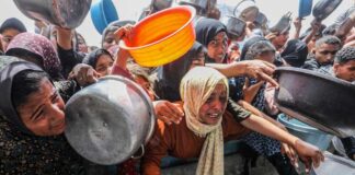 women and children reach with pots at a crowded aid distribution
