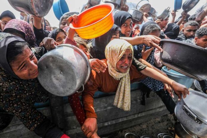 Palestinians,Receive,Hot,Meals,(takiya),From,The,Rafah,Charity,Kitchen women and children reach with pots at a crowded aid distribution