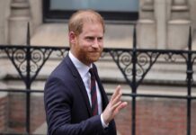 Charity Admits Torture—Harry Stays Silent A man in a suit smiling and waving outdoors