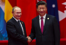 China’s Imperial Welcome: Putin Follows Trump Two international leaders shaking hands at a diplomatic event
