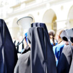 Federal Prosecutors Joke About PROSECUTING NUNS Group of nuns in black attire gathered outdoors, one holding a megaphone