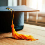 Graduation cap with yellow tassel on table