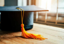 Graduation cap with yellow tassel on table