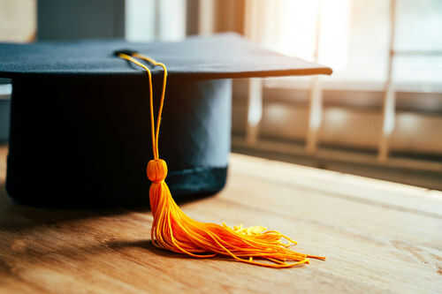 Graduation cap with yellow tassel on table