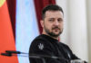 man in black sweatshirt at a podium looking to the side