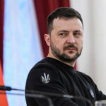 man in black sweatshirt at a podium looking to the side