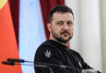 man in black sweatshirt at a podium looking to the side