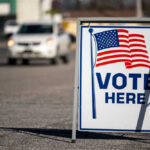 Vote Here sign with American flag.