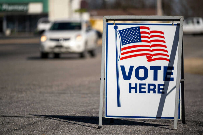 vote-here-409137028 Vote Here sign with American flag.