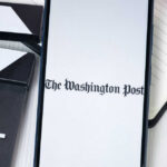 Phone displaying The Washington Post beside clapperboard.