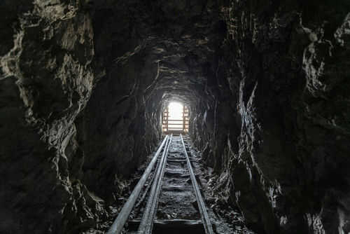 Dark tunnel leading to bright exit with tracks