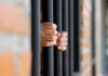 Hands gripping prison bars