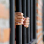 Court Move Could Gut Prisoner Protections Hands gripping prison bars