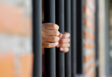 Hands gripping prison bars
