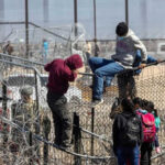 Is Washington Rewarding Illegal Hires? People climbing barbed wire fence wearing backpacks and hoodies