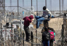 Is Washington Rewarding Illegal Hires? People climbing barbed wire fence wearing backpacks and hoodies