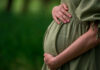 Pregnant person holding their belly in a green dress