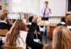 Classroom with student raising hand teacher speaking front