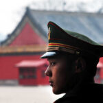 Beijing Tests Red Lines — What Breaks First? A military guard in uniform standing in profile against a historical building