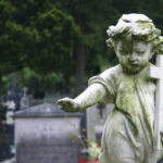Weathered angel statue holding a cross in a cemetery