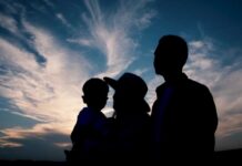 Silhouette of a family against a colorful sunset sky